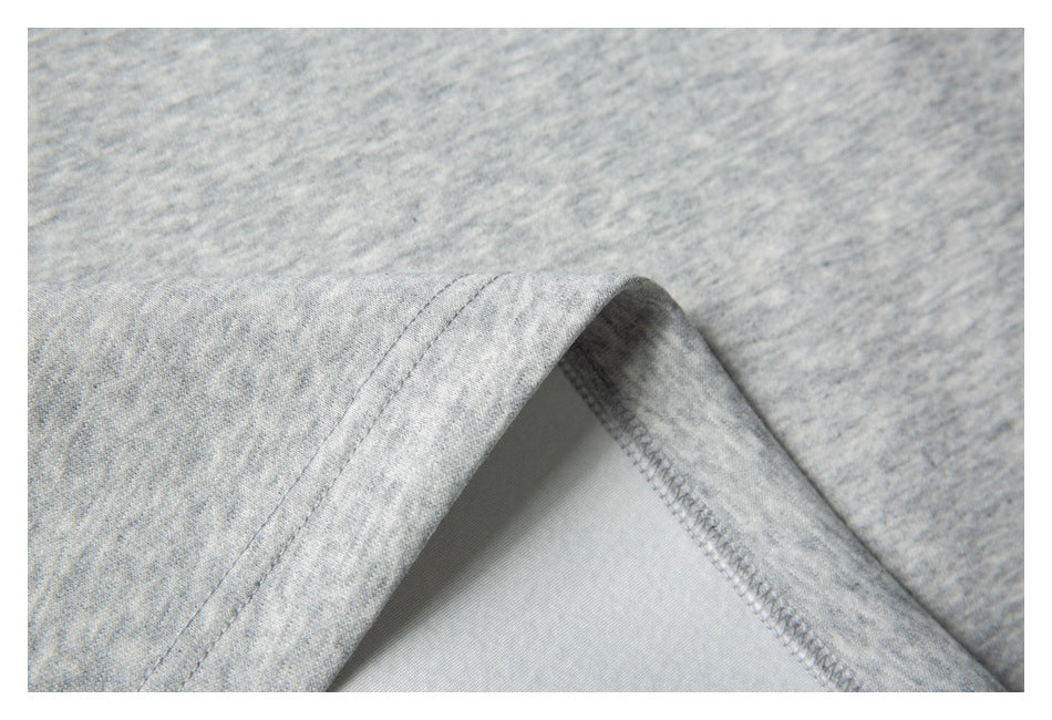 Close-up of a folded garment edge showing the light gray heather fabric and overlocked inner seam.