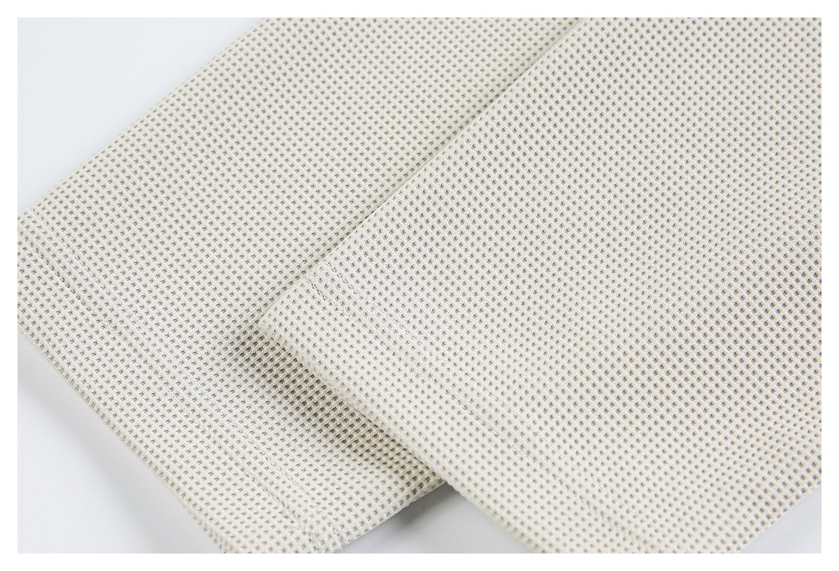 Close-up of ivory waffle-knit fabric folded to show its small textured grid.