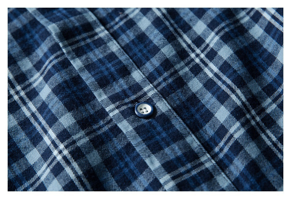 Close-up of blue, black, and gray plaid fabric with a light button on the placket.