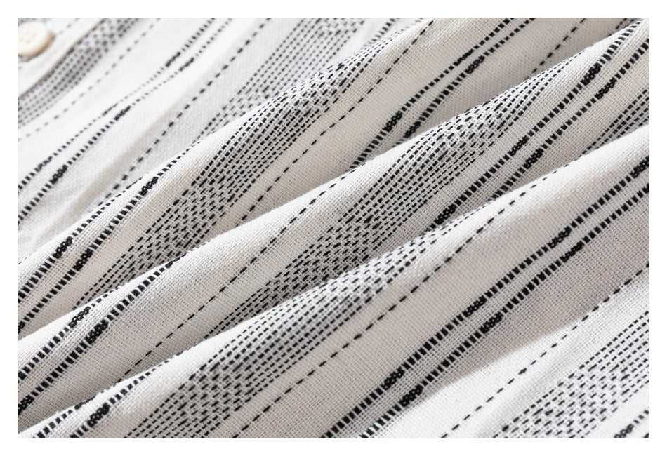 Close-up of white fabric with narrow black woven stripe patterns and a small white button at the edge.