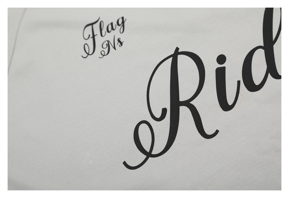 Close-up of black script lettering printed on light gray shirt fabric.