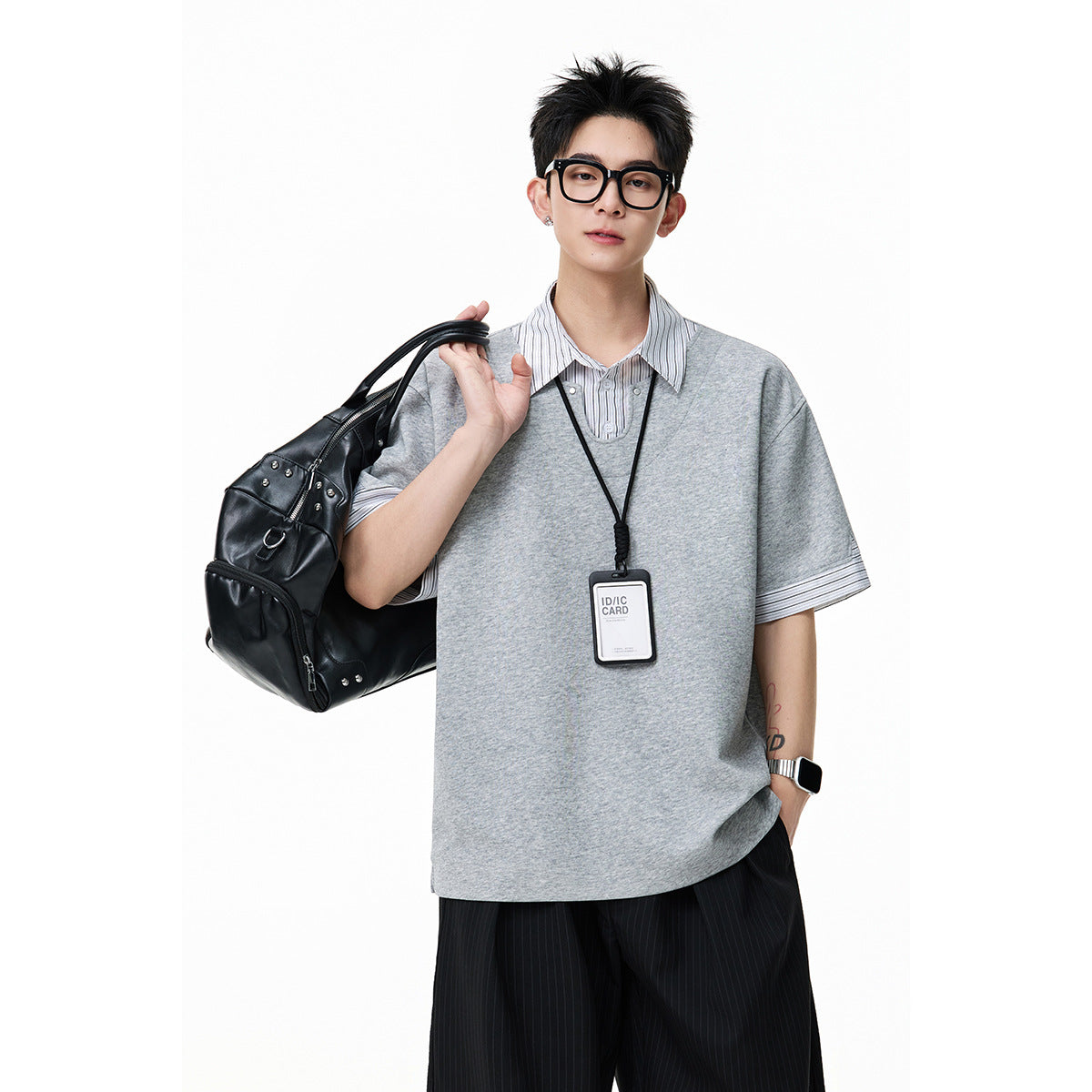 Model in a light gray layered short-sleeve top with pinstriped collar and cuffs, carrying a black bag.