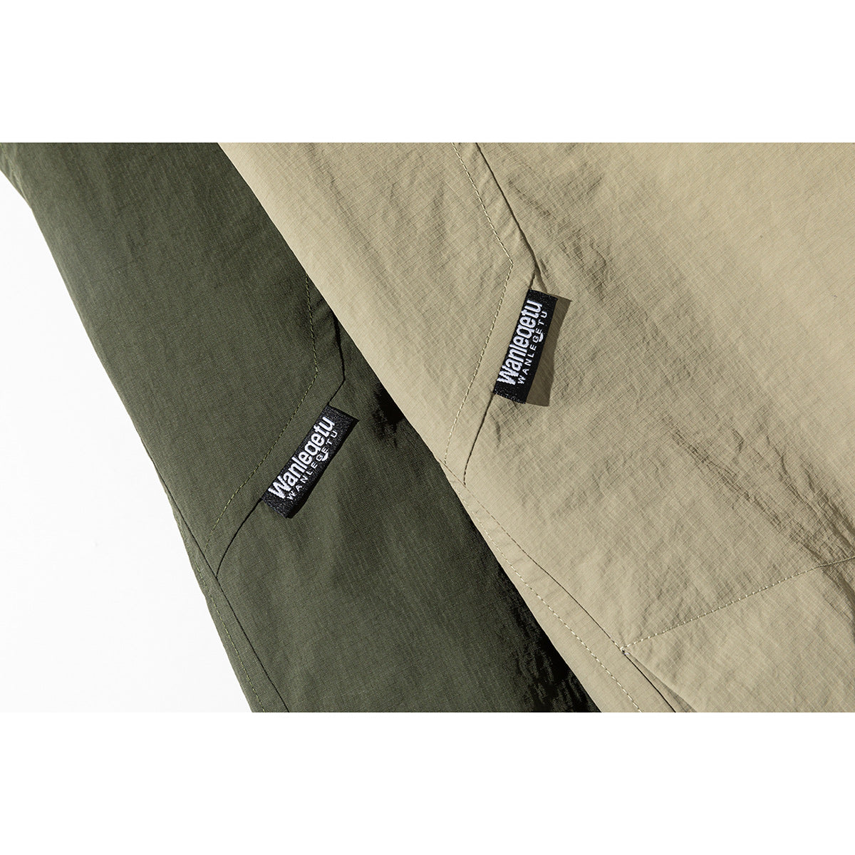 Close-up of dark olive and khaki jacket fabric with small sewn brand labels and visible seam stitching.