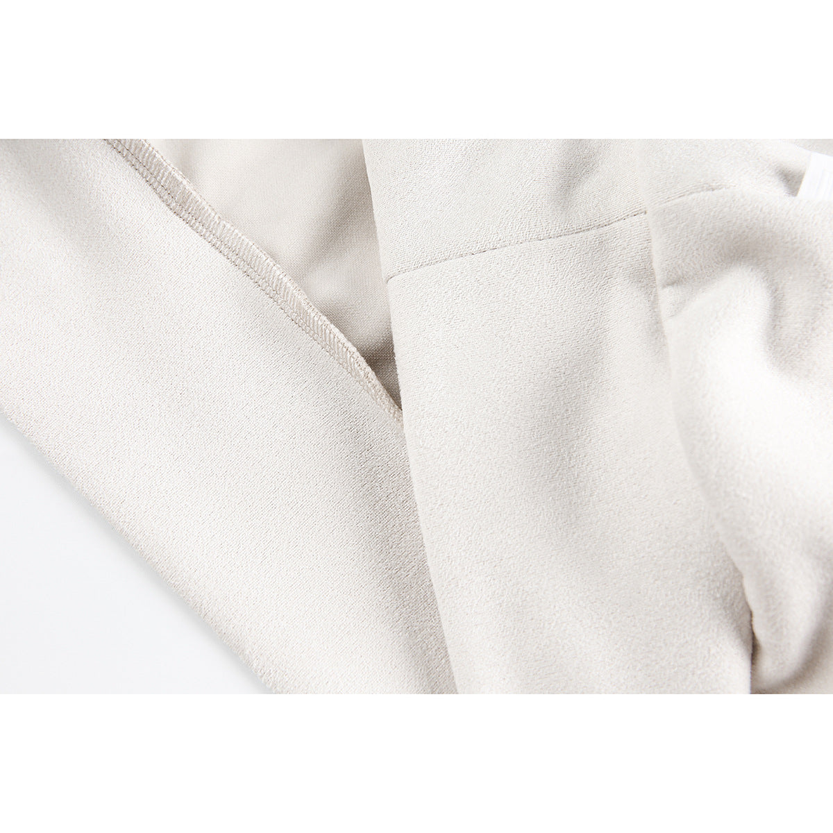 Close-up of ivory sweatshirt fabric, an overlocked seam, and a folded sleeve cuff.