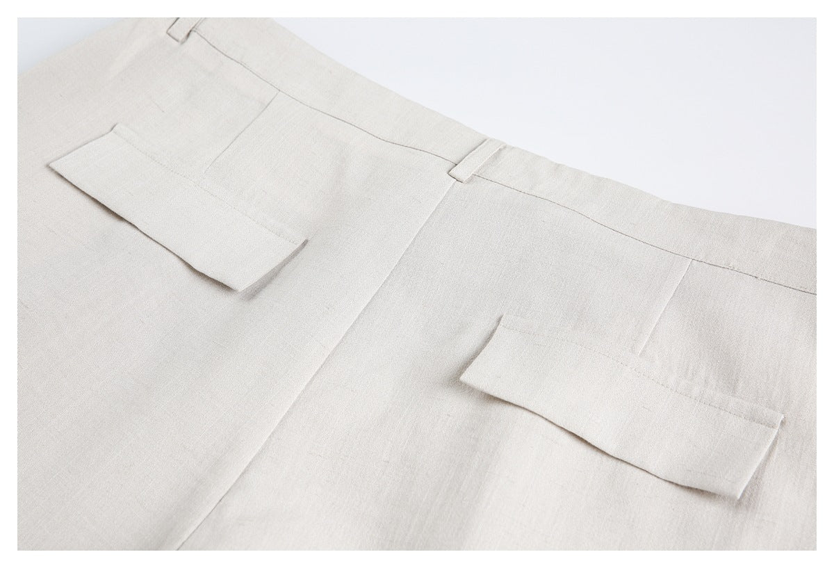 Close view of the back waist and two rectangular pockets on light beige trousers.