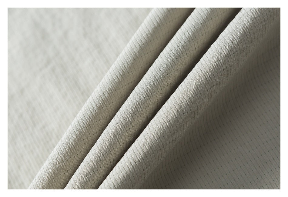 Close-up of folded light beige fabric showing fine ribbed texture and subtle dark lines.