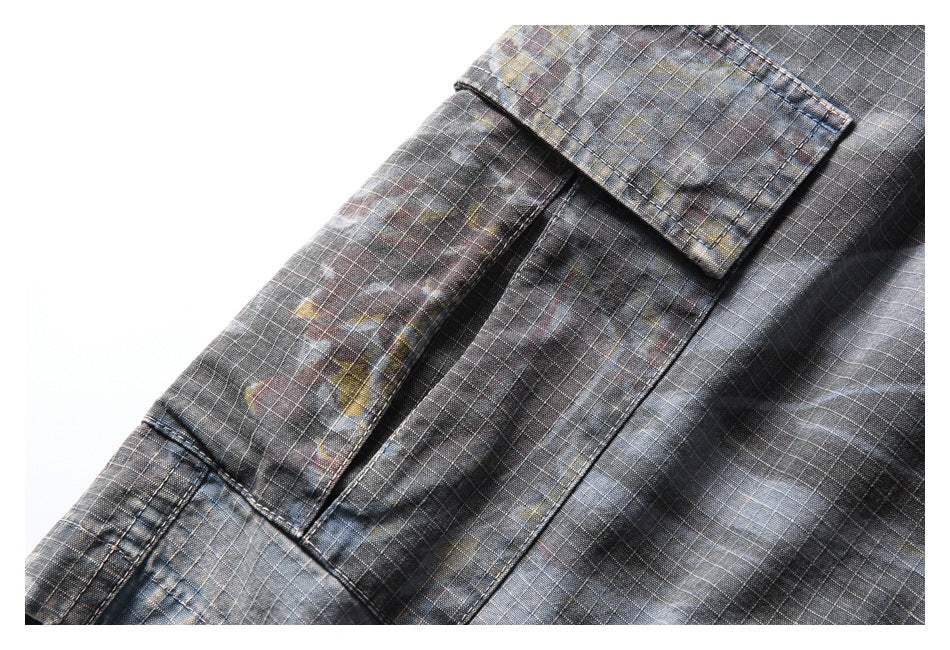 Close-up of a flap pocket on dark gray plaid trousers with subtle muted multicolor accents.