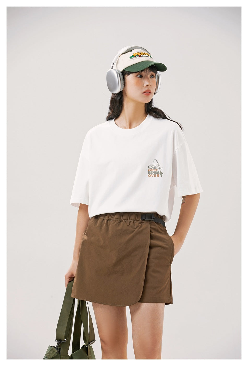 Model wearing an oversized white graphic T-shirt and brown wrap-front shorts.