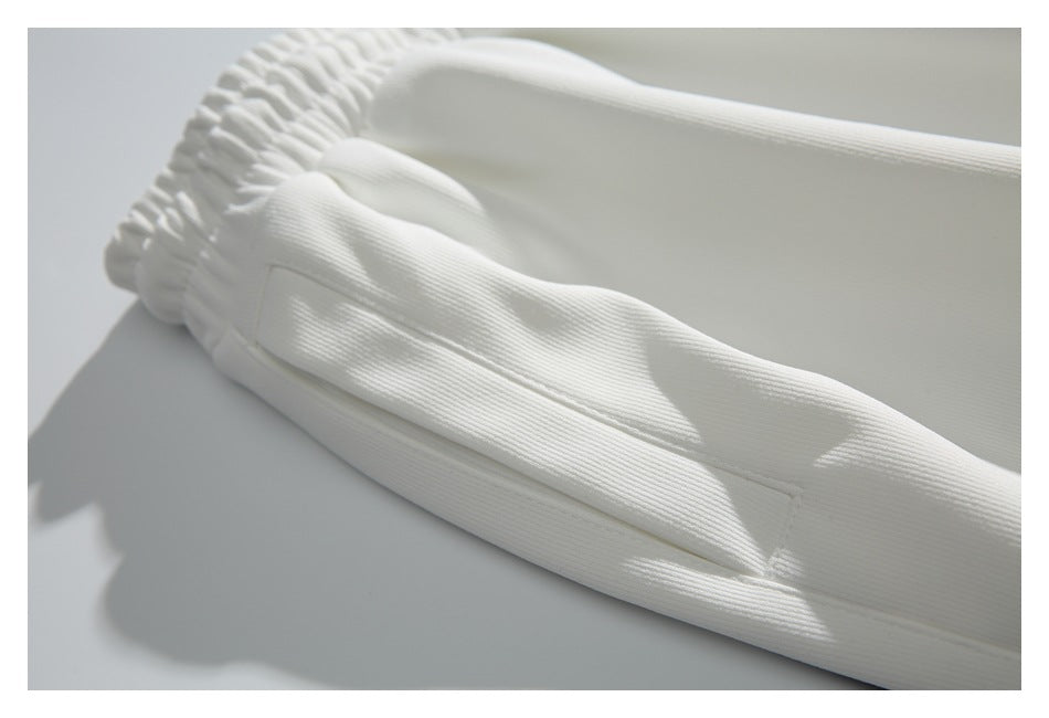 Close-up of the white pants' elastic waistband and stitched side panel.