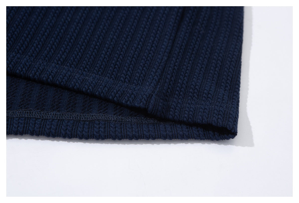 Close-up of a navy ribbed garment hem showing its underside and overlock stitching.