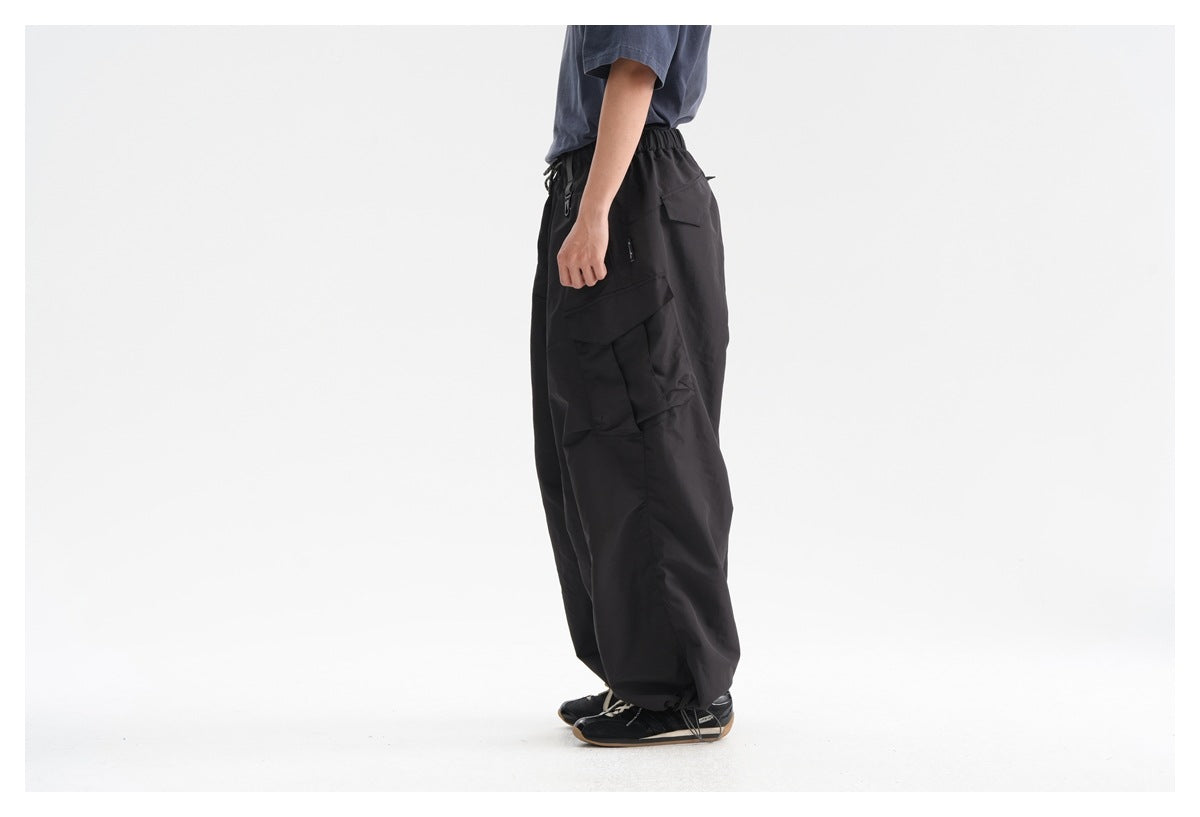 Side view of a model wearing loose black cargo pants with oversized cargo pockets and an elastic waist.