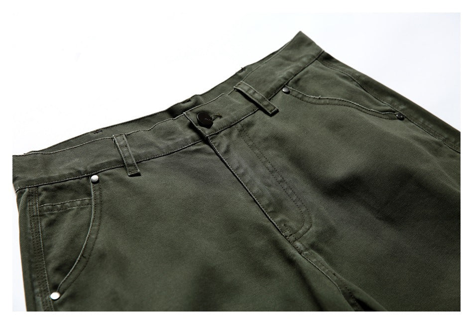 Close-up of olive green trousers showing the waistband, button, belt loops, fly, and front pockets.