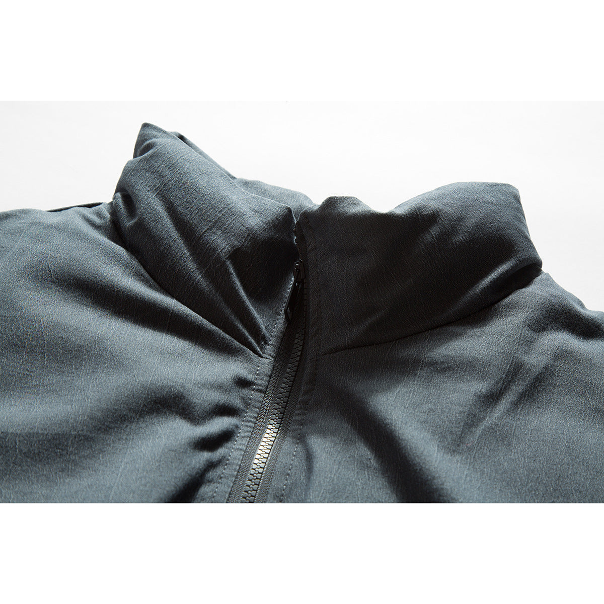 Close-up of a dark blue-gray jacket's stand collar and central black zipper.