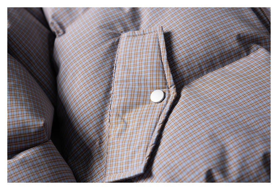 Close-up of a light-colored snap on a flap pocket of a blue and tan checked jacket.