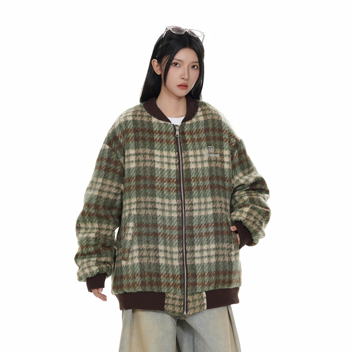 Model wearing a green, cream, and brown plaid zip jacket with dark brown ribbed trim.