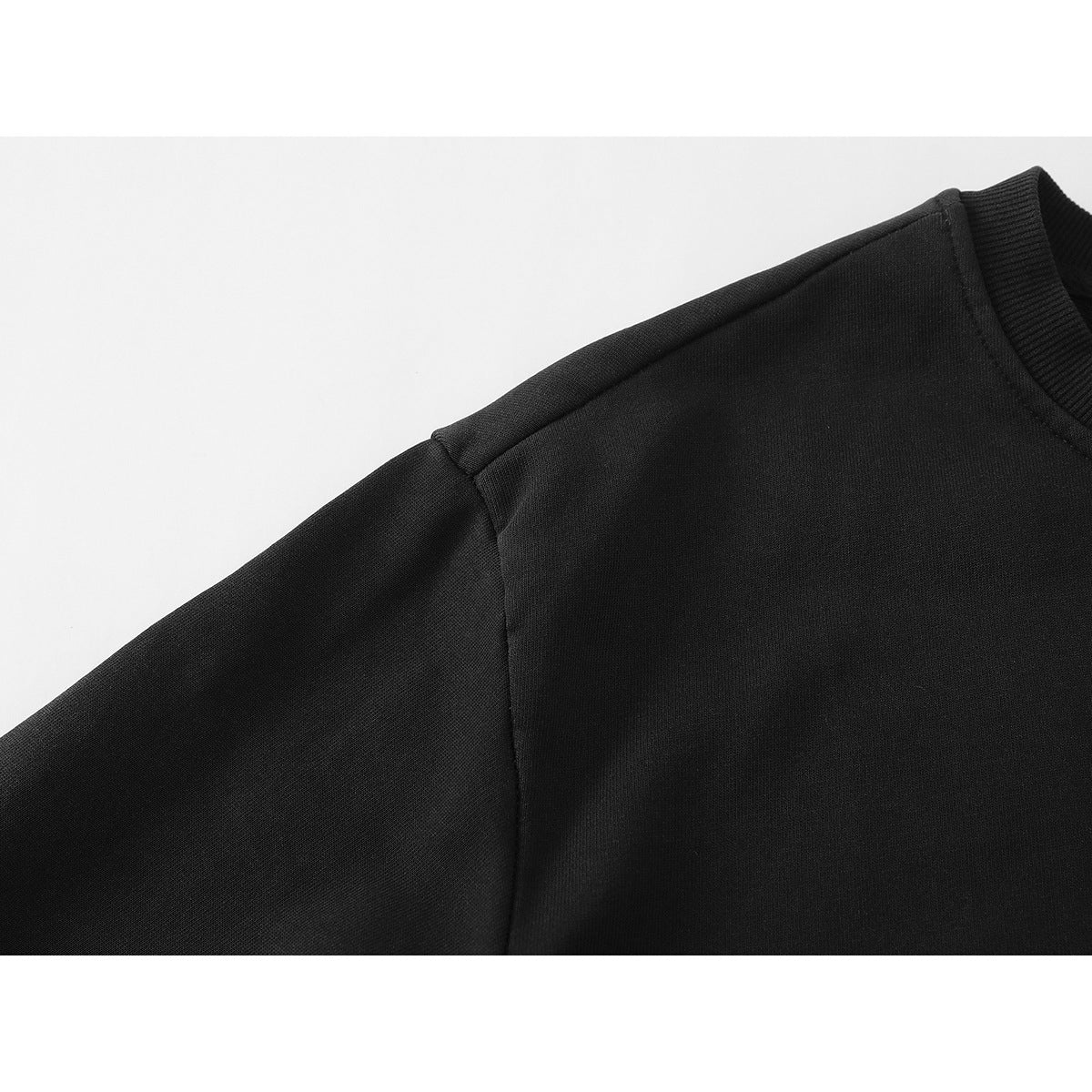 Close-up of the black sweatshirt shoulder seam and upper sleeve.