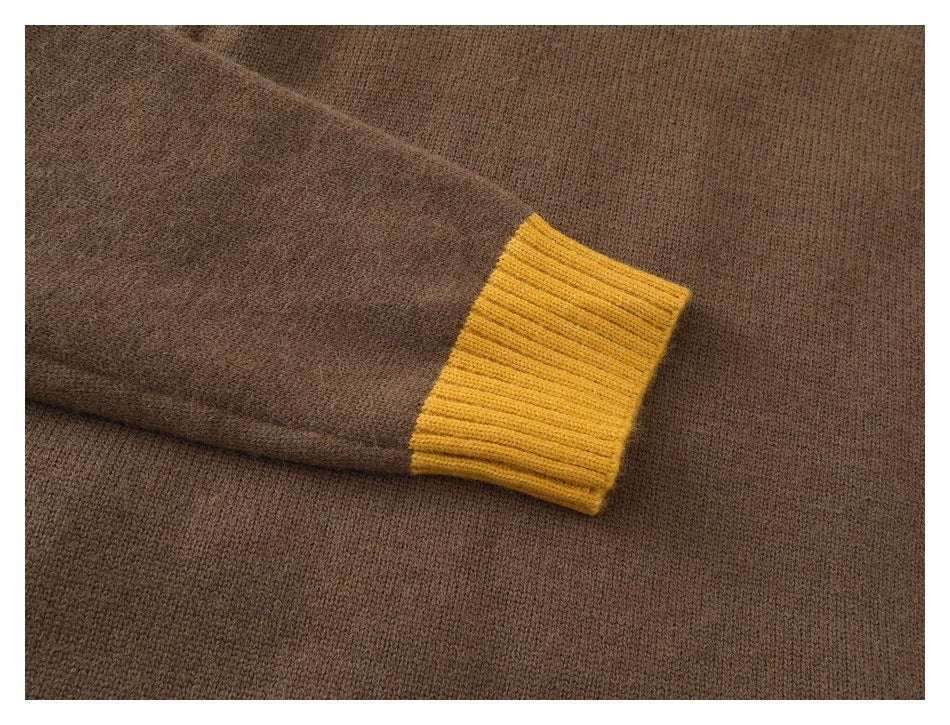 Close-up of a brown sweater sleeve with a mustard yellow ribbed cuff.