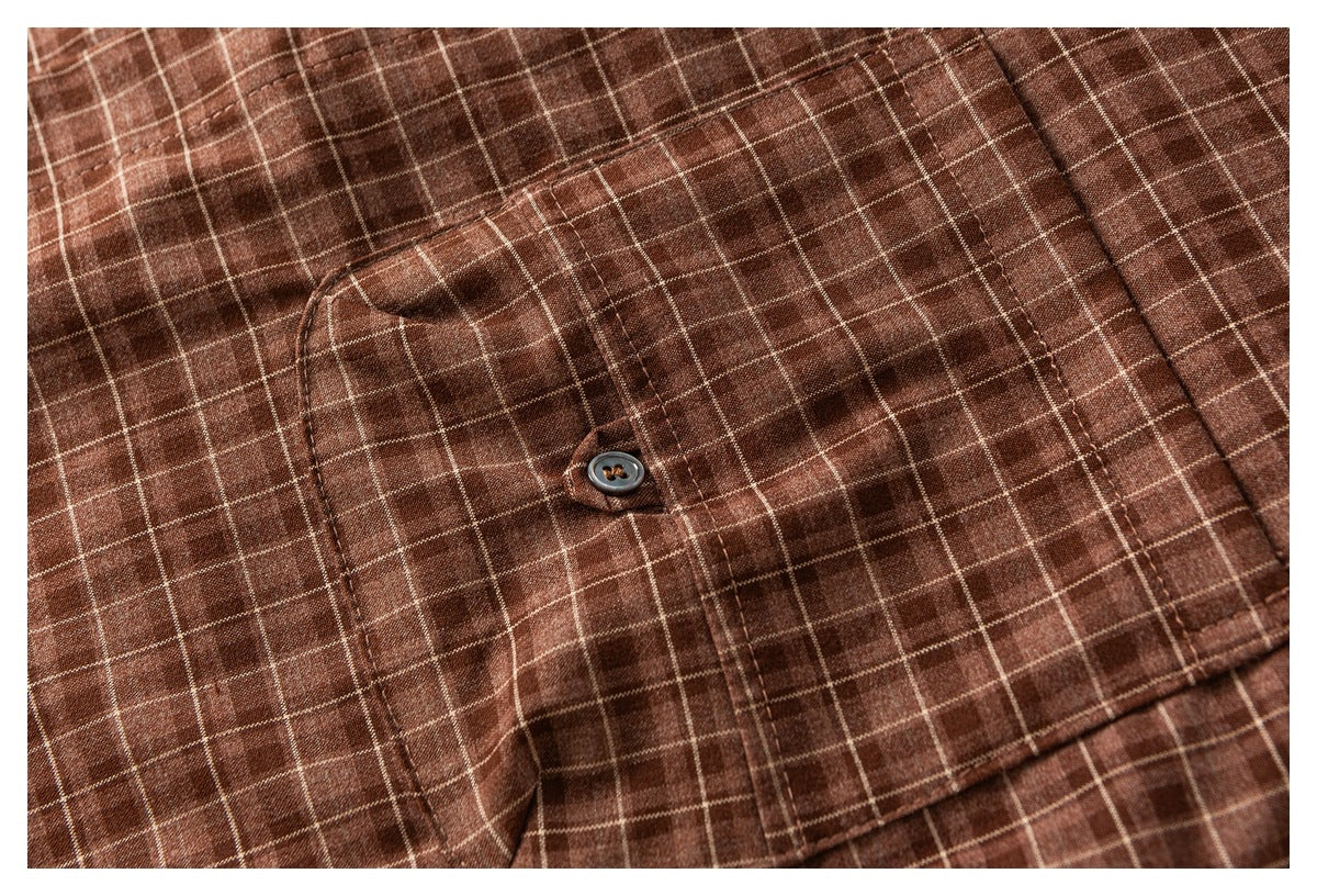 Close-up of a buttoned chest pocket on a brown windowpane-check shirt.