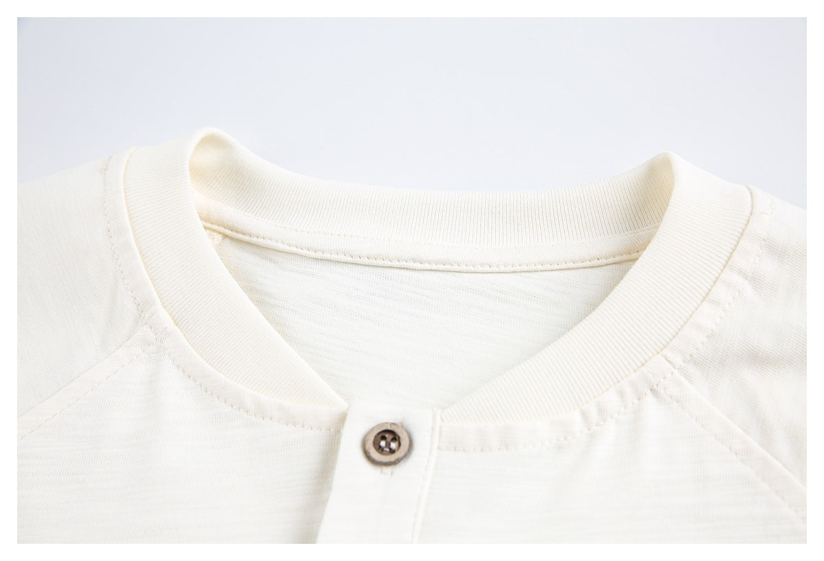 Close-up of an ivory shirt's ribbed crew neckline, raglan seams, and single button at the collar.