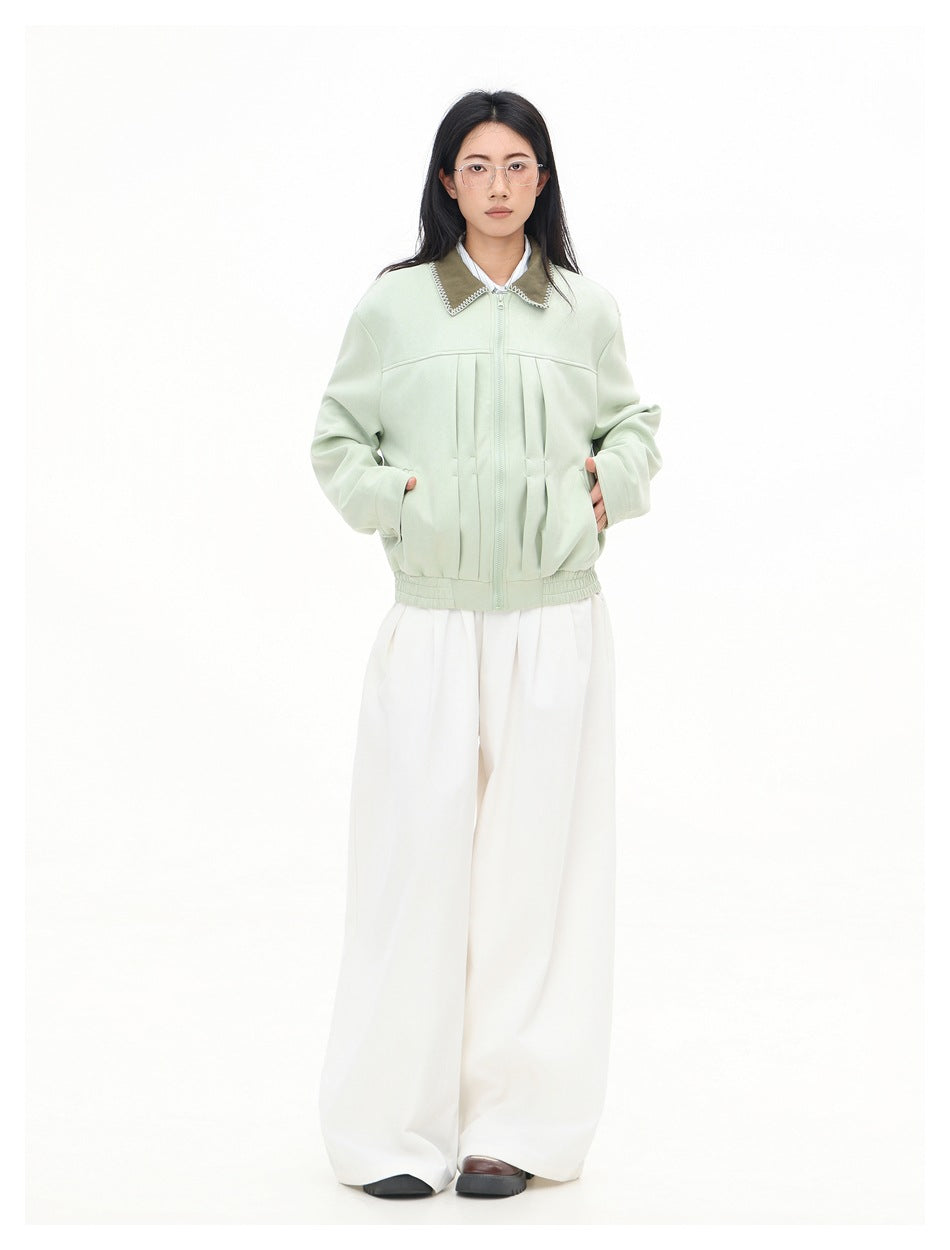 Full-length front view of a model wearing a zipped pale mint jacket with a contrasting collar and white wide-leg trousers.