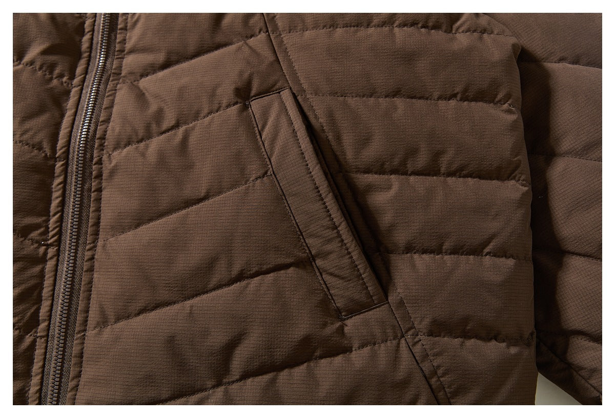 Close-up of a brown quilted jacket's angled front pocket opening beside the zipper.