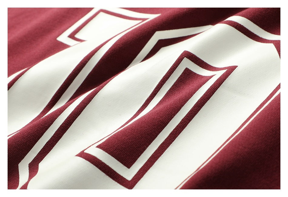 Close-up of a burgundy shirt's large white-and-burgundy outlined number print on folded fabric.