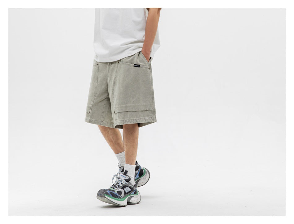 Angled view of a model wearing loose light gray-green shorts with large front patch pockets.