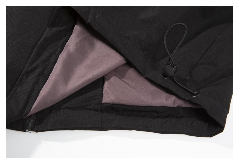 Close-up of black garment interior showing mauve lining, a hem seam, and an adjustable drawcord toggle.