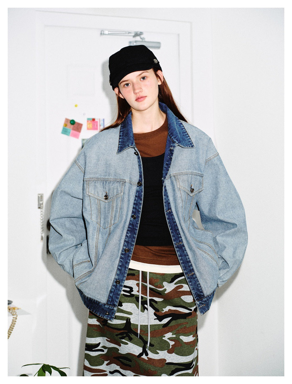 Model with hands in pockets wearing a loose light blue denim jacket with dark blue collar over layered tops