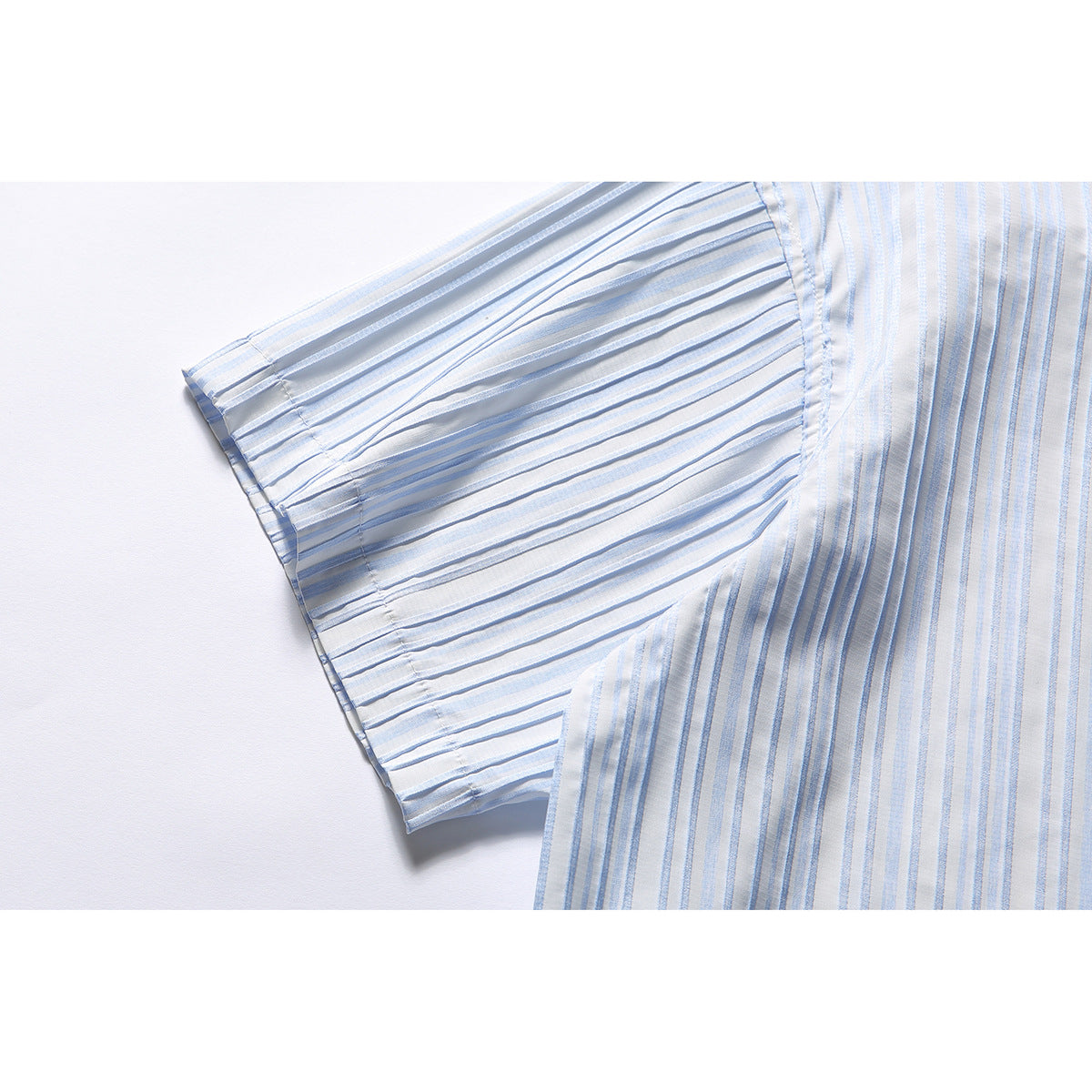 Close-up of the short sleeve and striped body of a white shirt with pale blue vertical stripes.