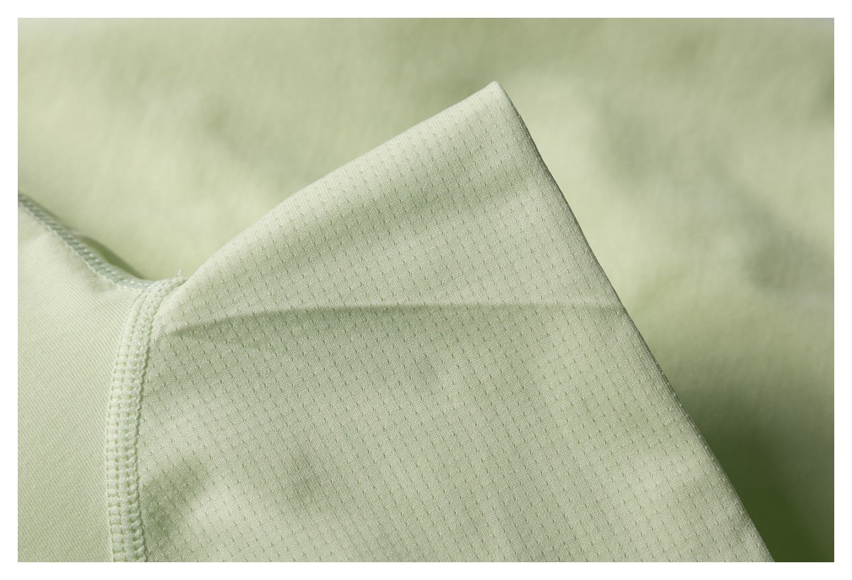 Close-up of pale lime jacket fabric showing a small perforated texture and stitched seam.