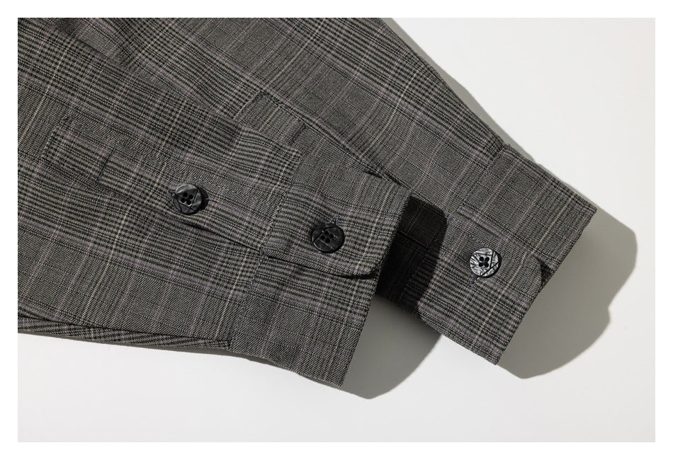 Close-up of a gray plaid garment sleeve with a buttoned cuff and dark buttons.
