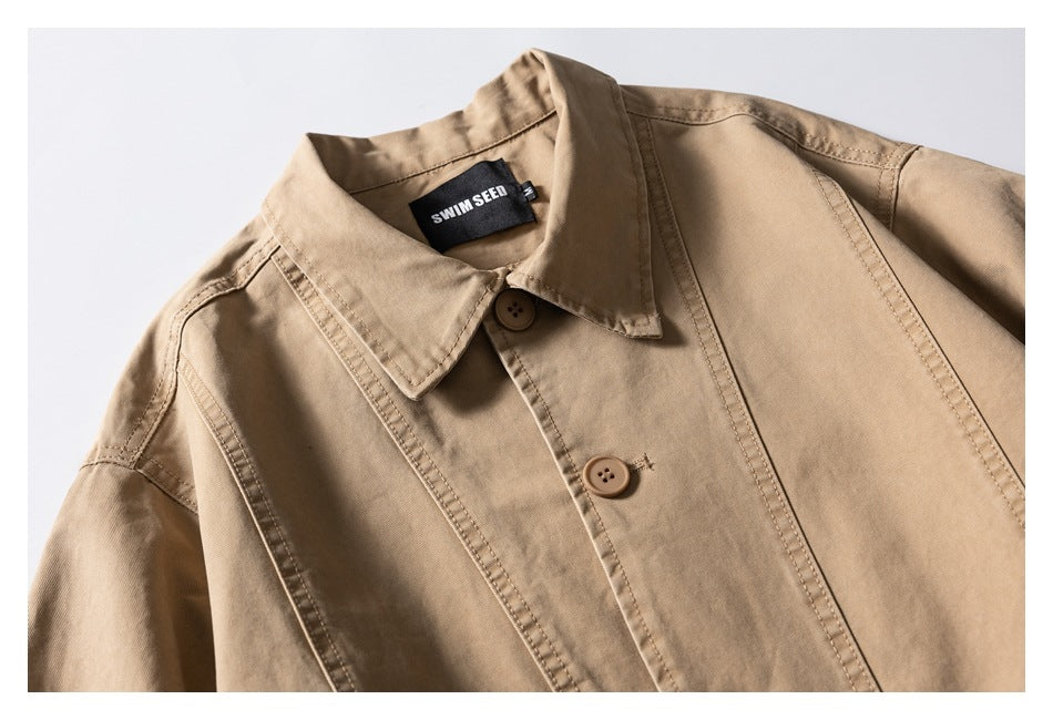 Close-up of a tan jacket collar, button, and stitched seams; a black neck label is visible.