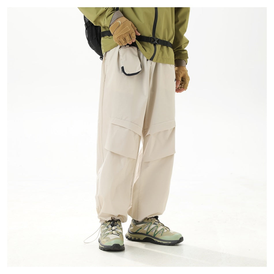 Angled side view of a model wearing loose ivory trousers with layered knee panels and a black-trimmed pocket.