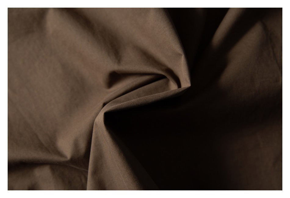 Close-up of brown garment fabric gathered into folds, showing its surface and drape.