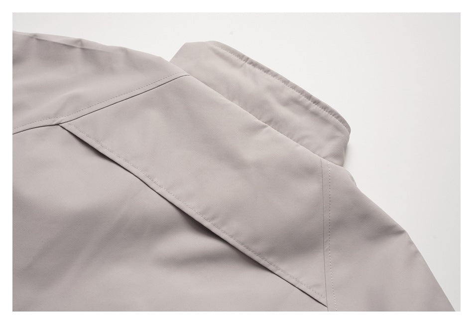 Close-up of the light taupe jacket's back seam and overlapping fabric panel.