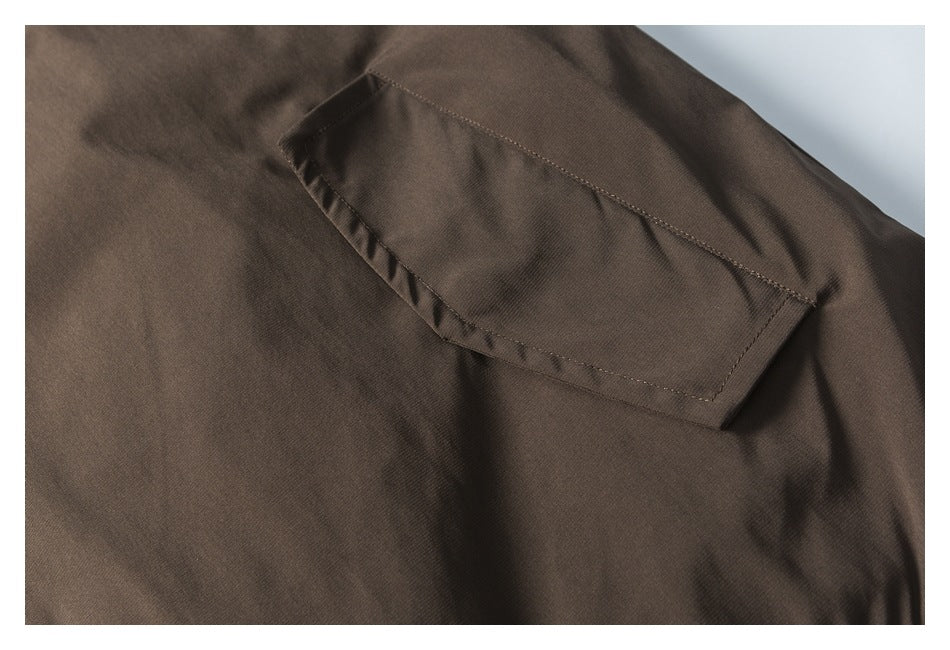 Close-up of a flap pocket stitched onto the dark brown jacket.