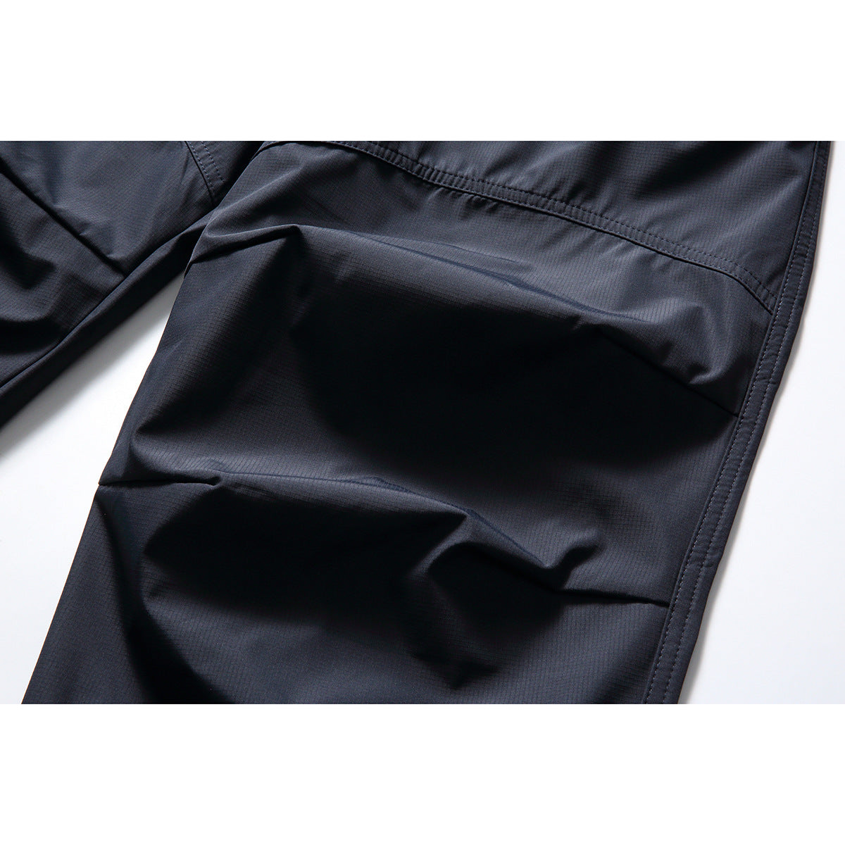Close-up of dark navy pants showing the textured fabric and stitched panel seams.