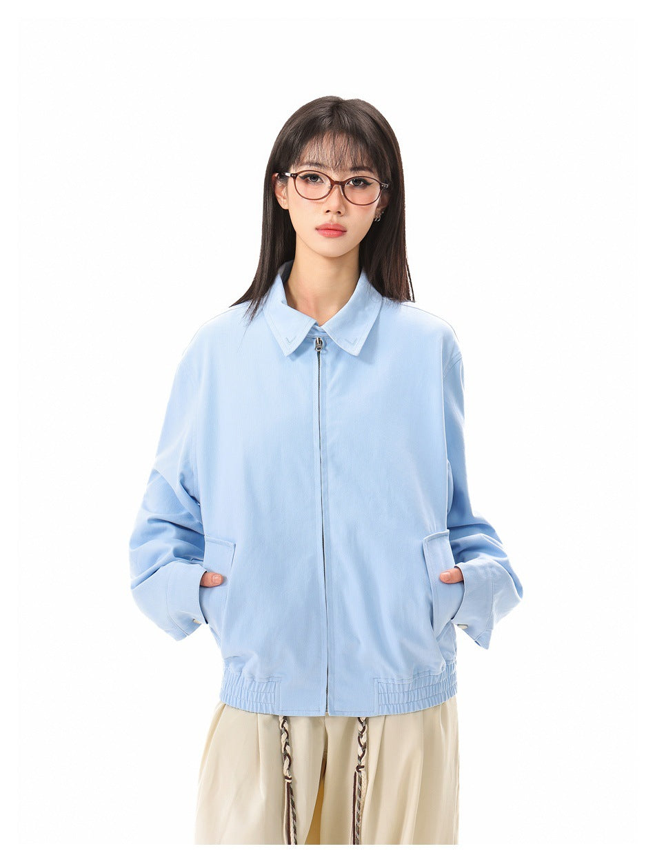 Closer front view of a model wearing a light blue zip jacket with a pointed collar, roomy sleeves, and front pockets.