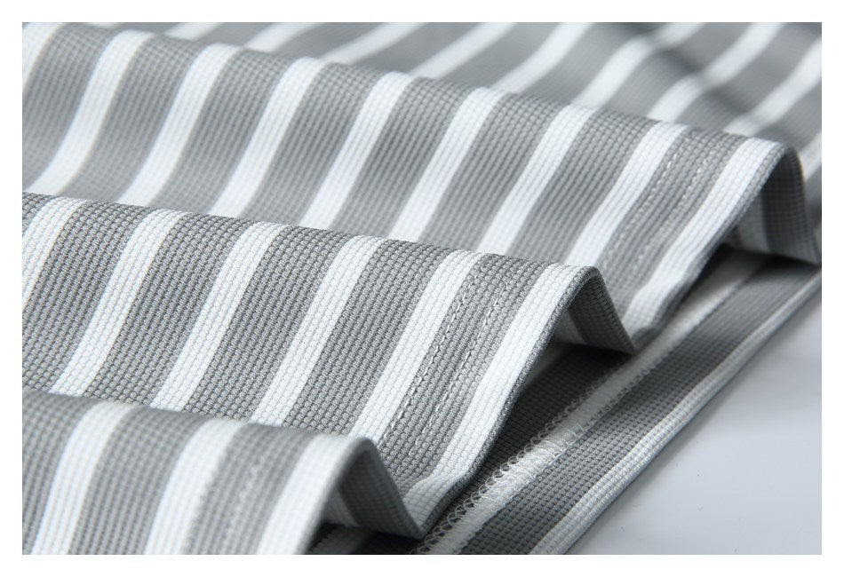 Close-up of folded gray-and-white striped fabric showing parallel stripes and a finished overlocked edge.