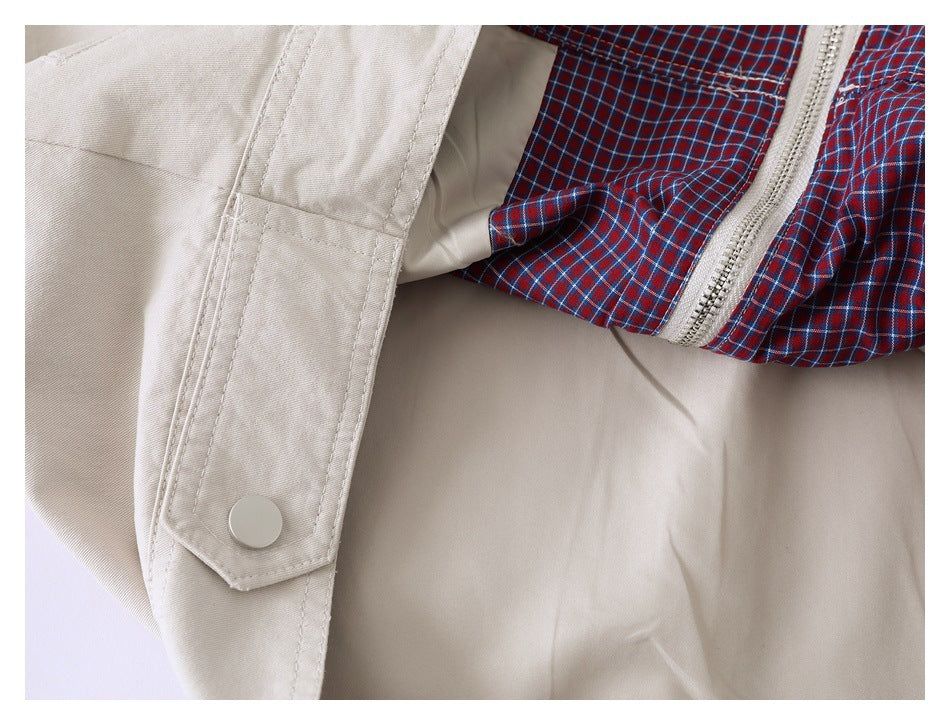 Close-up of a beige jacket showing a snap-tab fastening, red-and-blue plaid lining, and zipper.