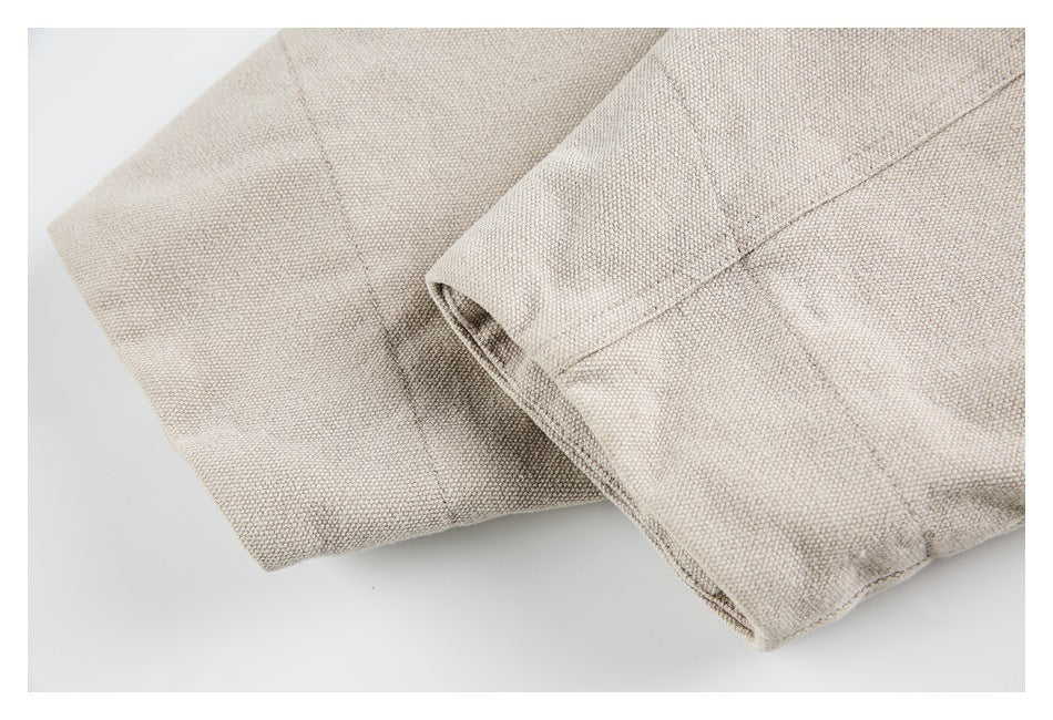 Close-up of light beige textured fabric folded to show stitched seams.
