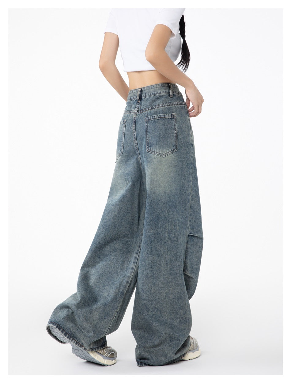 Angled back view of a model wearing faded blue wide-leg jeans with two rear pockets.