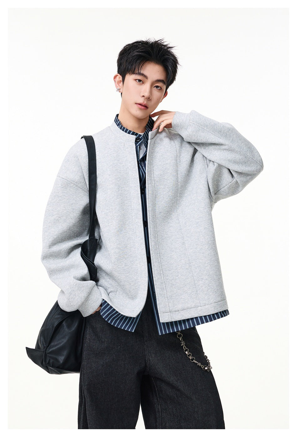 Model wearing a light gray oversized stand-collar jacket over a blue striped shirt.