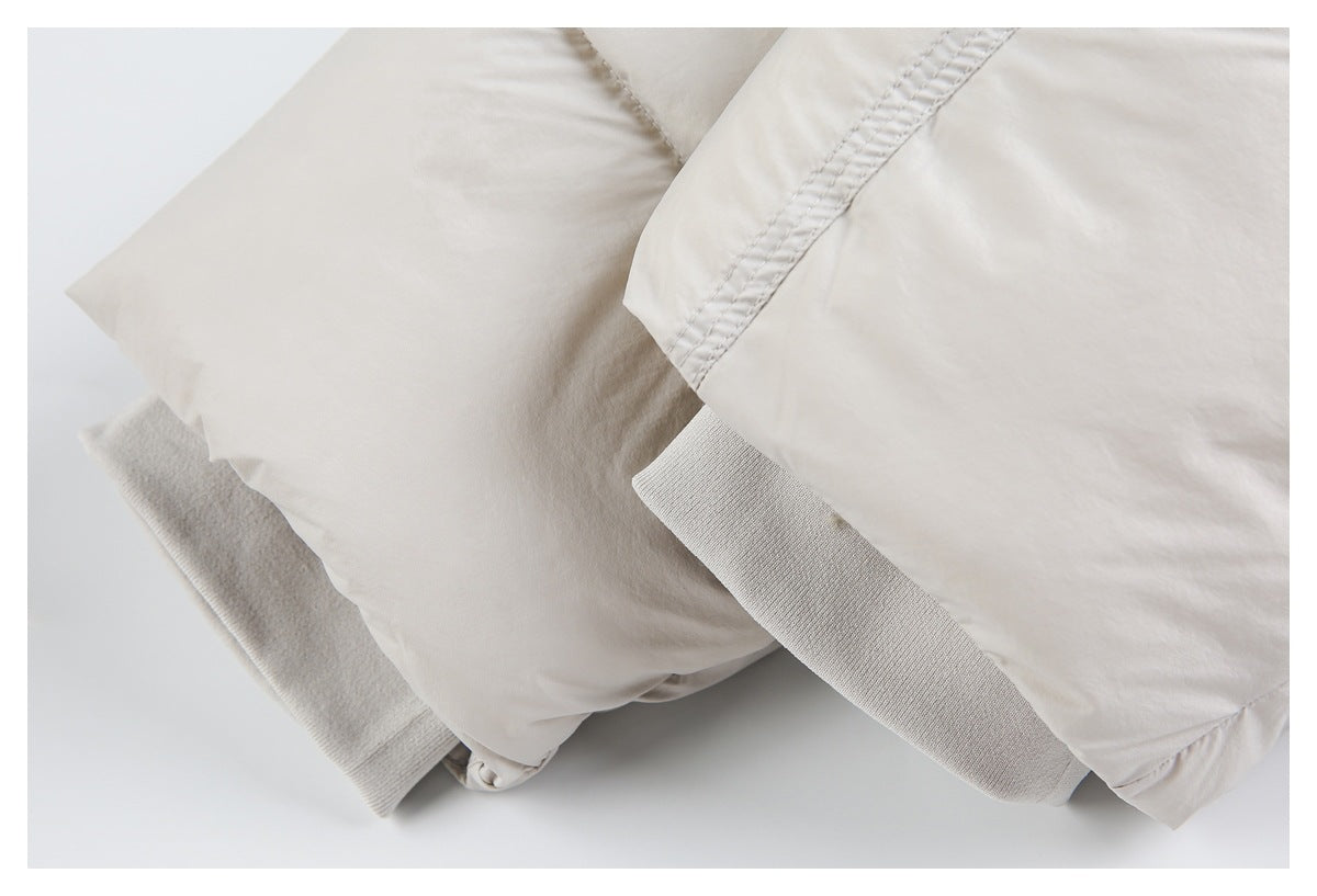 Close-up of an off-white padded jacket showing a ribbed knit cuff or hem beside a quilted panel.