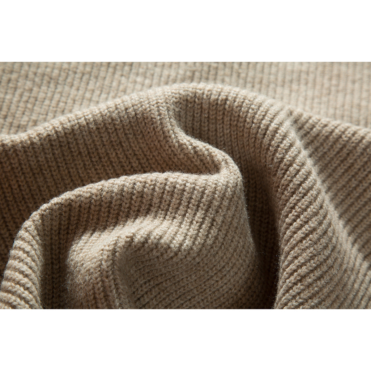 Close-up of beige knit fabric folded to show its collar and textured stitching.