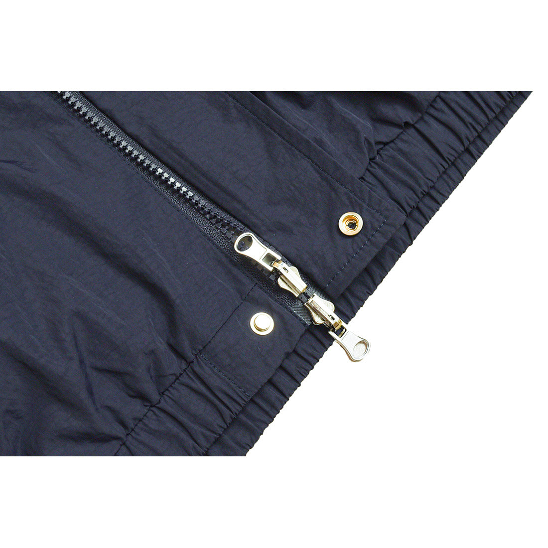 Close-up of the navy jacket's zipper with two pulls, snap fasteners, and an elasticized edge.