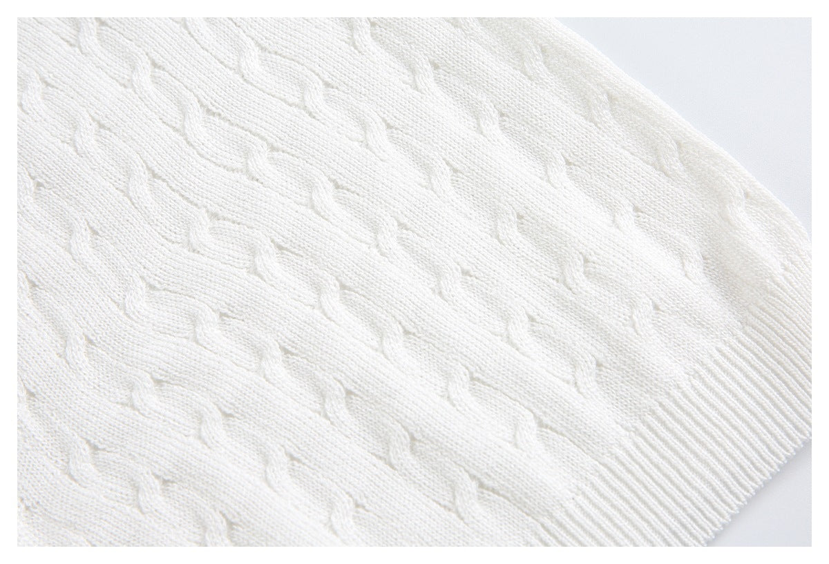 Close-up of the ivory garment's textured knit body and ribbed hem edge.