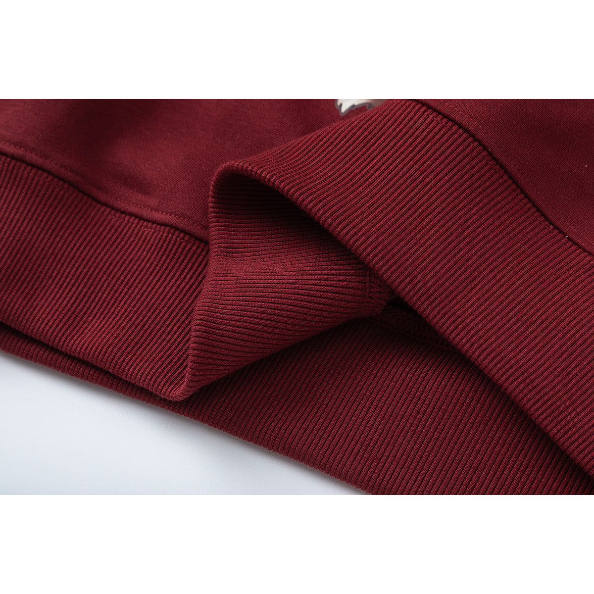 Close-up of burgundy sweatshirt fabric and folded ribbed hem or cuff.