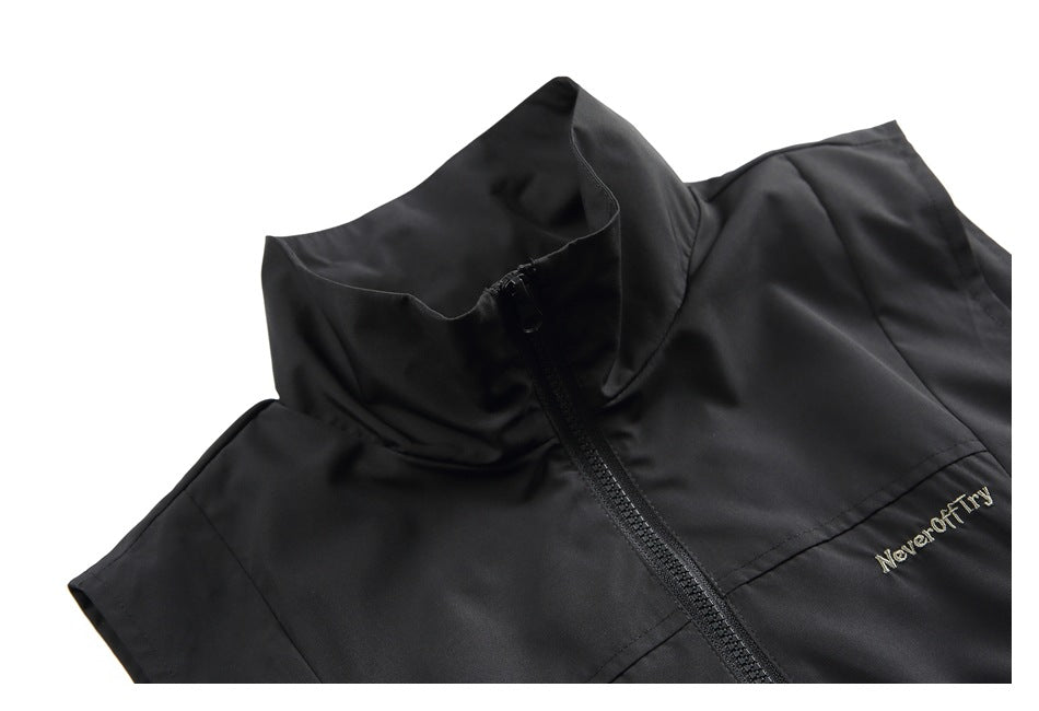 Close-up of a black vest's high collar, front zipper and small embroidered text on the chest.